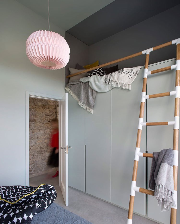 Dormitorio con cama sobre armario con escalera de madera. luminaria suspendida rosa