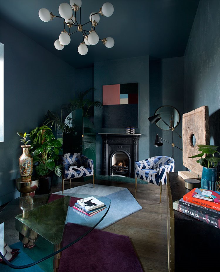 Salón con paredes y techos pintado en tonos azules, butacas en terciopelo azul, mesa de centro con sobre de cristal y chimenea