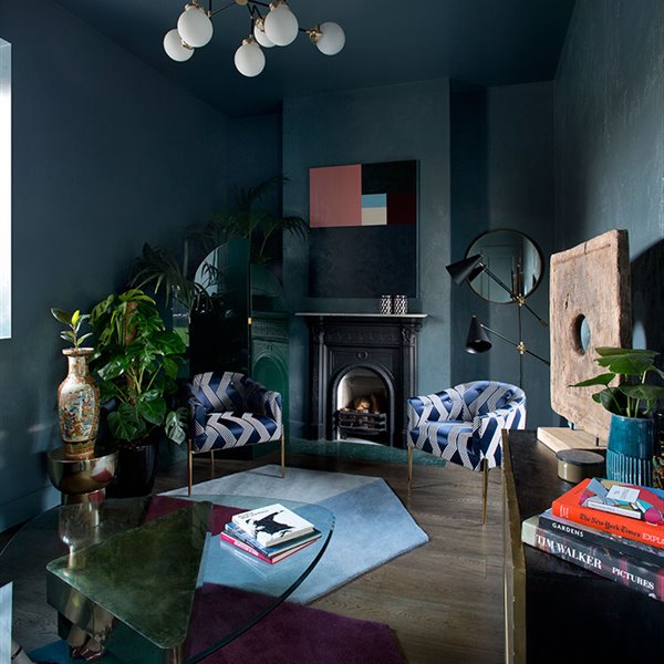 Salón con paredes y techos pintado en tonos azules, butacas en terciopelo azul, mesa de centro con sobre de cristal y chimenea