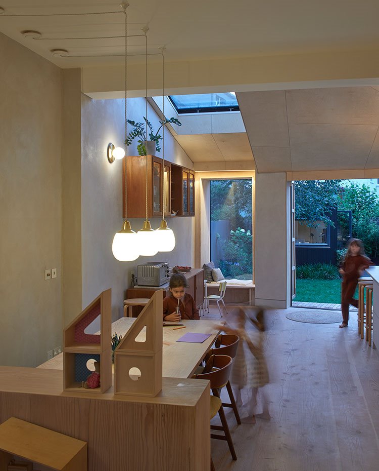 Comedor junto a zona abierta de día, con mesa, sillas y módulos de almacenaje en madera