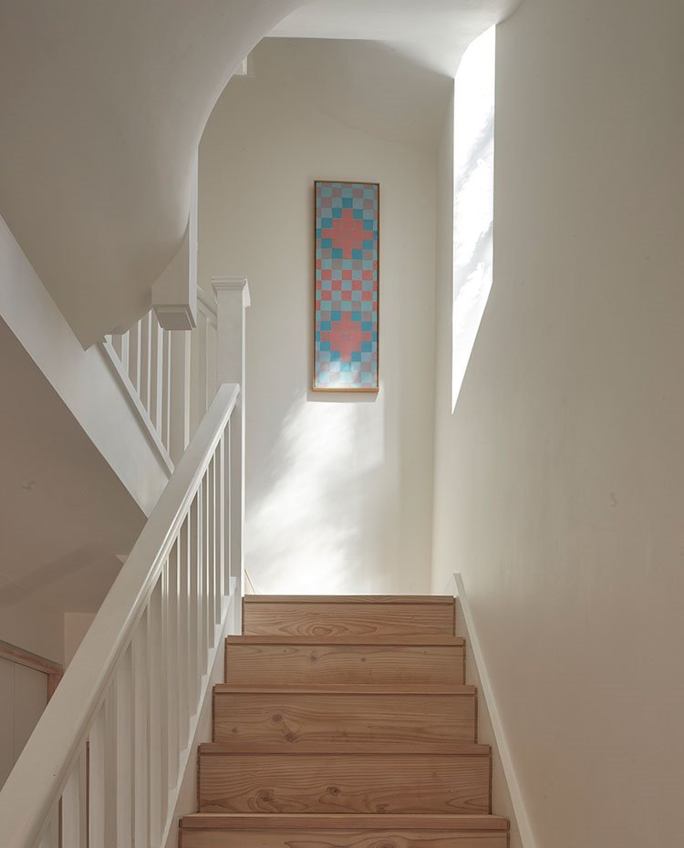Escaleras revestidas de madera y pasamanos pintados en blanco