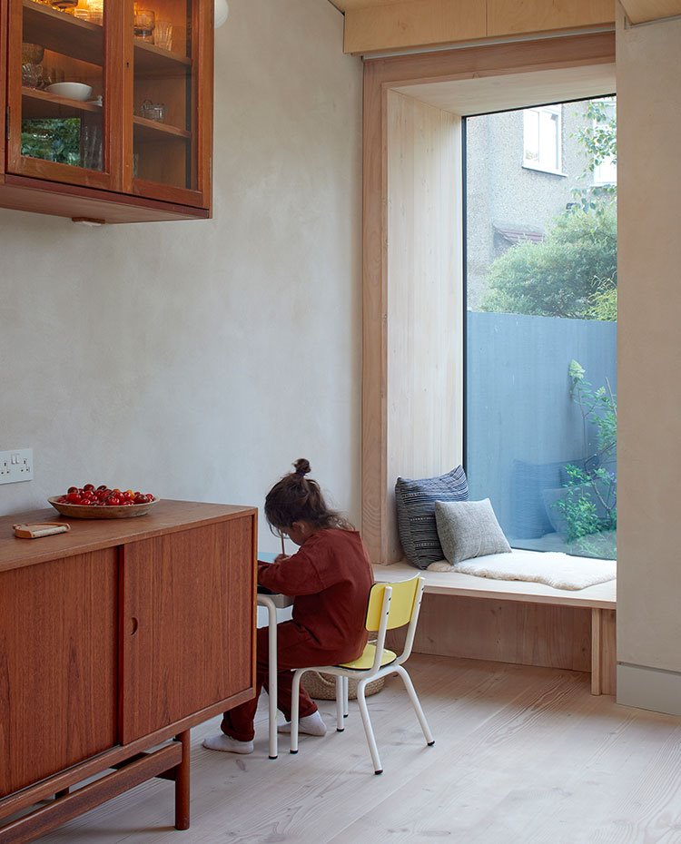 Mobiliario vintage en madera, mesa y silla infantil y hueco junto a ventana para zona de descnaso