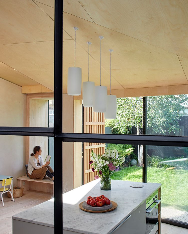 Perfilería en negro sobre cristal junto a isla de cocina y jardín exterior