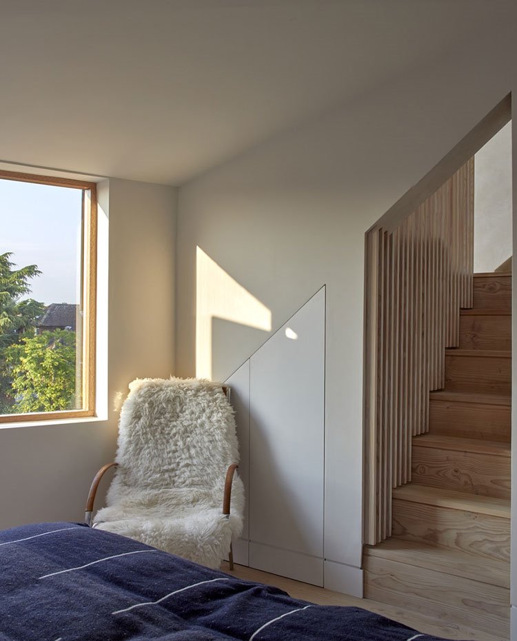 Asiento revestido de piel a los pies de la cama y escaleras revestidas de madera
