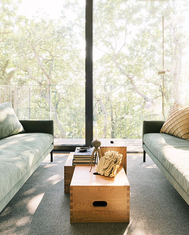 Cajones de madera a modo de mesas de centro, sofás en verde y alfombra en gris