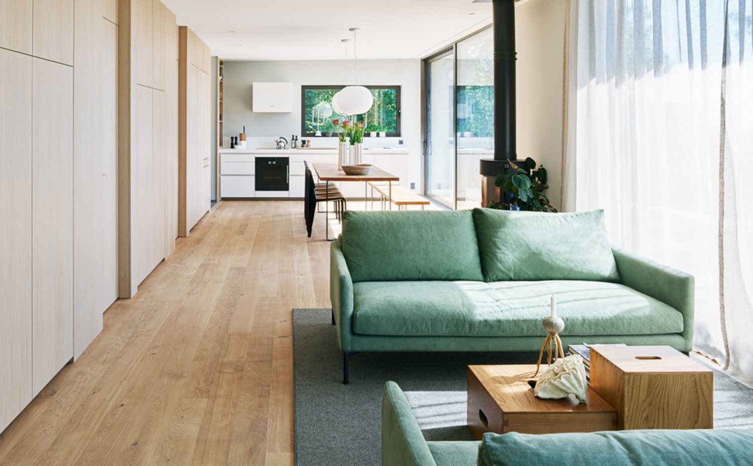 Salón con comedor y cocina, en planta abierta, sofá en verde y carpintería a medida