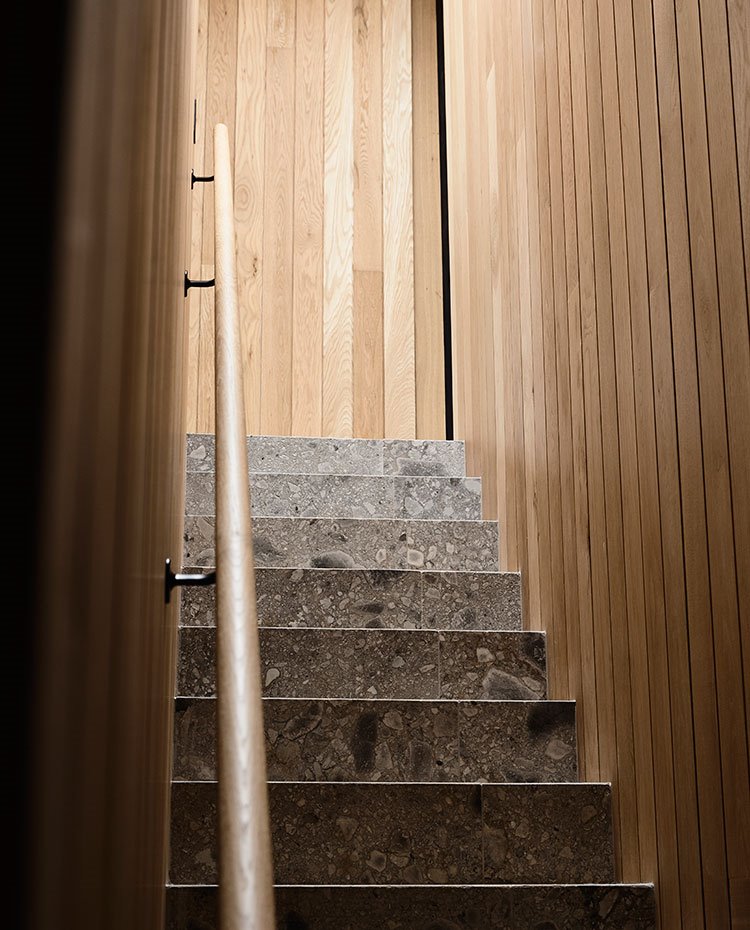 Escaleras con pasamanos de madera y paredes paneladas en madera, suelo a juego con el resto de la casa