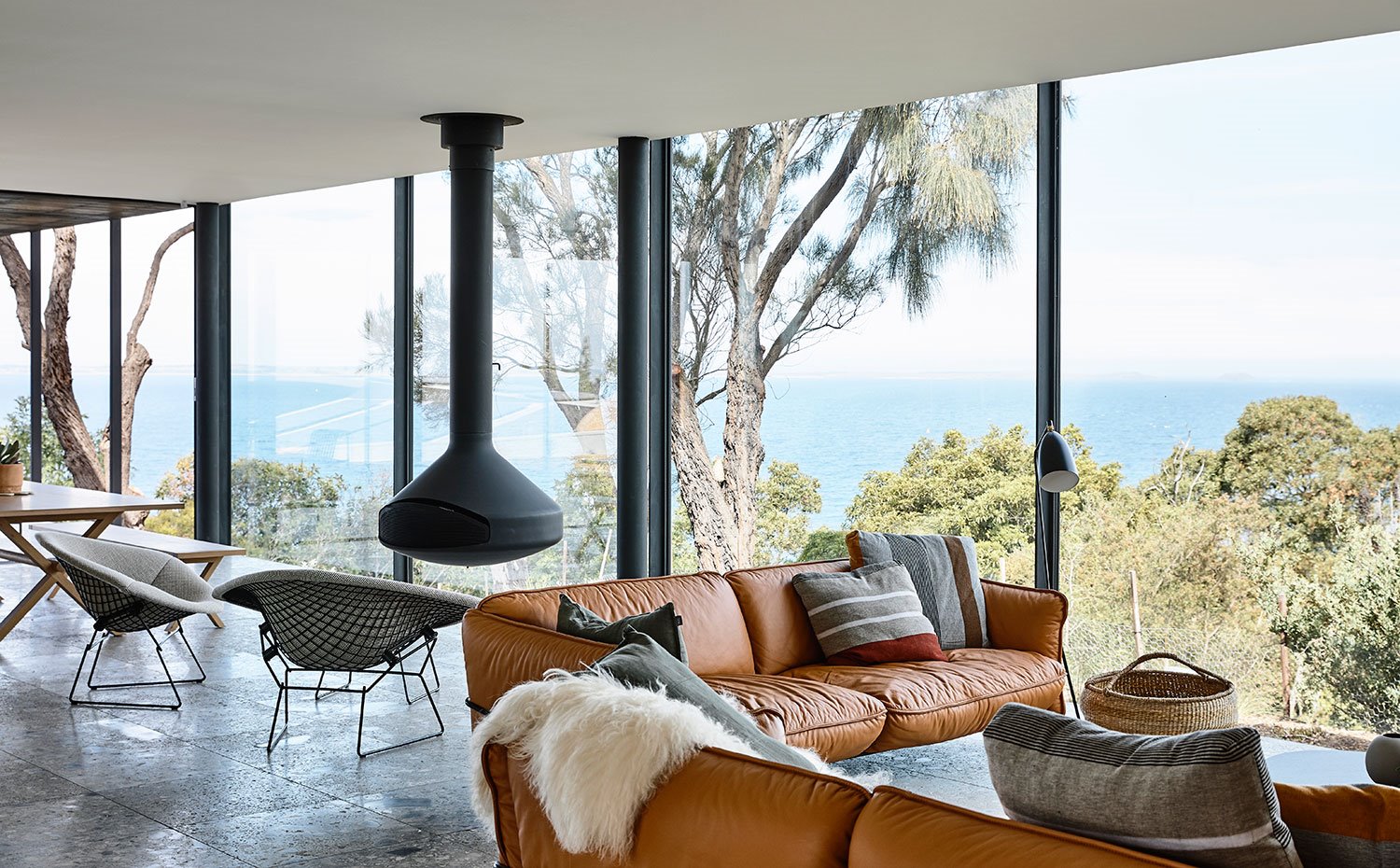 Salón con cerramiento de cristal y vistas al bosque y mar de fondo