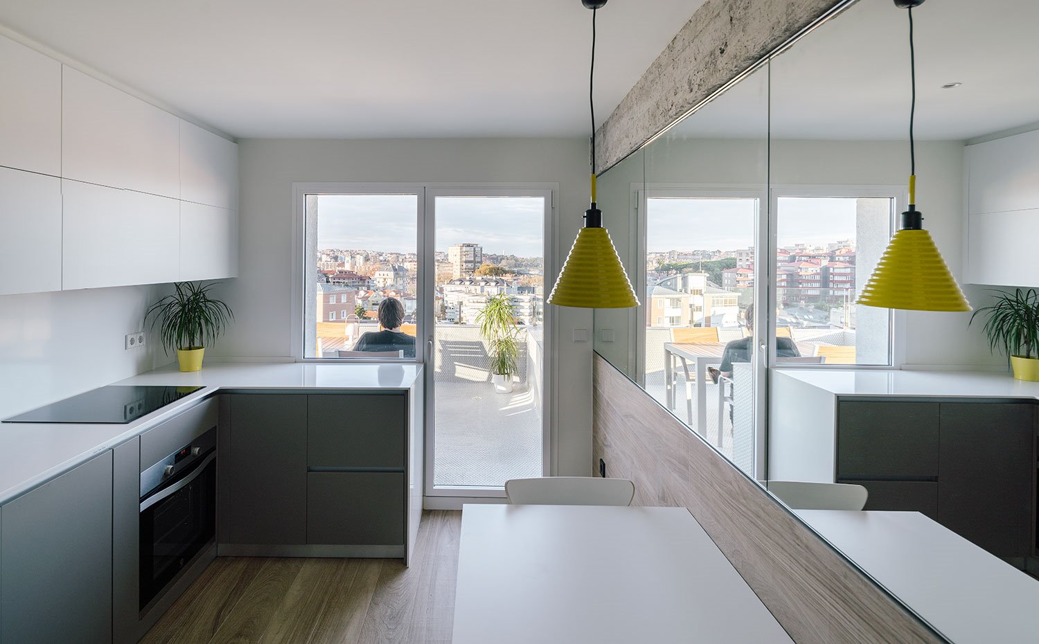 Cocina con mobiliario superior en blanco e inferior en gris, luminaria con pantalla en amarillo