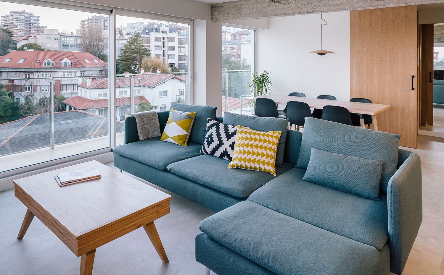 Salón con sofá con chaise-longue, mesa de centro de madera, con comedor en la parte trasera