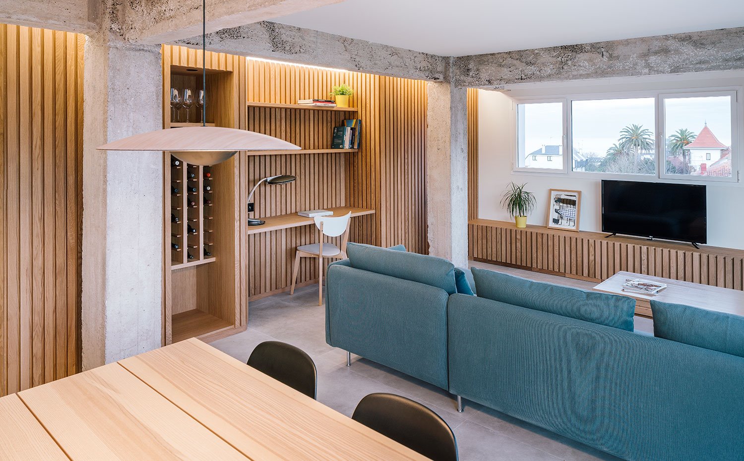 Zona de estar con comedor, salón y zona de trabajo con frente panelado de madera