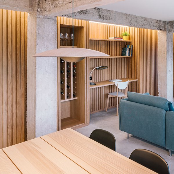 Zona de estar con comedor, salón y zona de trabajo con frente panelado de madera