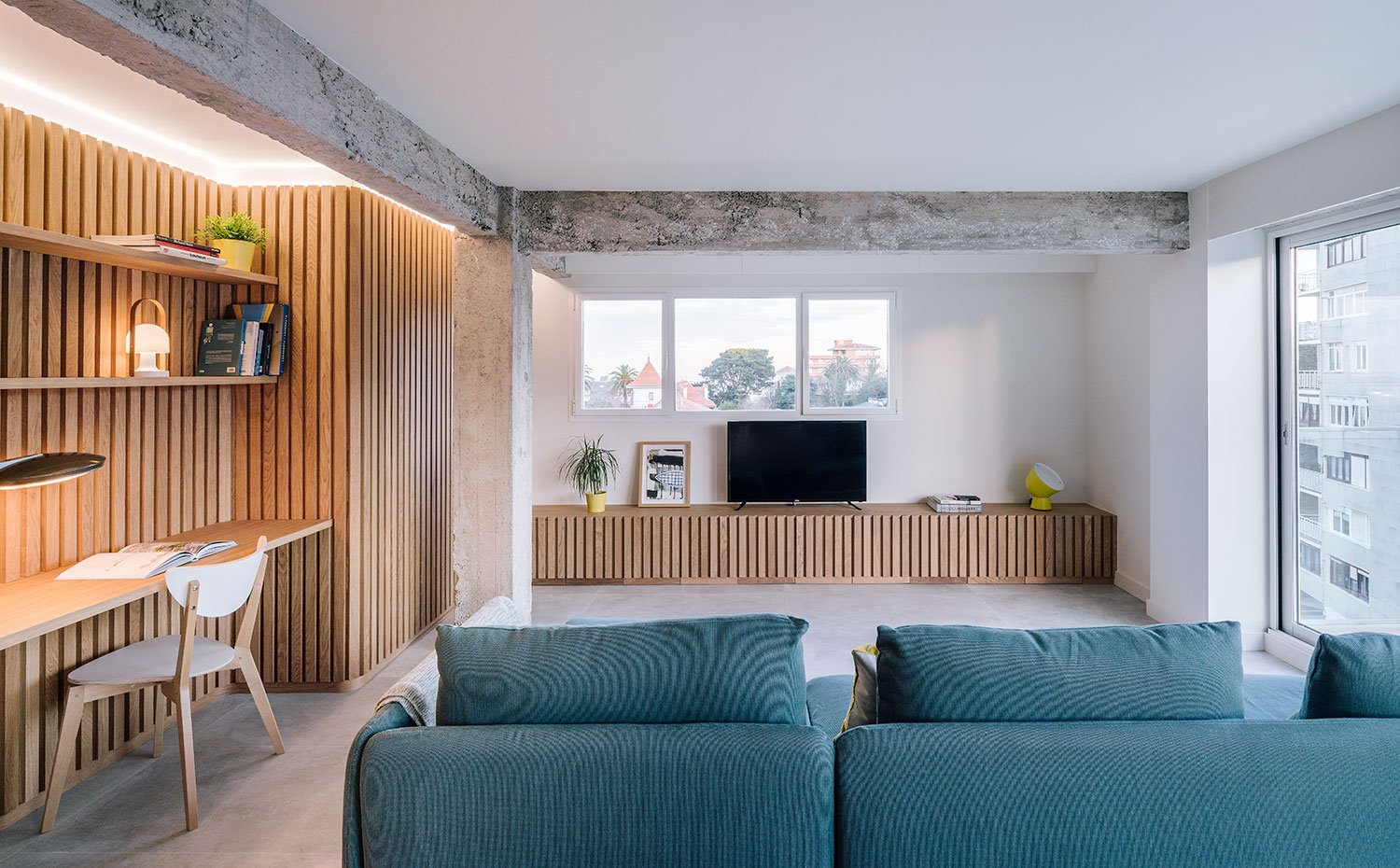 Zona de trabajo junto a sofá en azul cobalto y frente a mueble bajo televisor