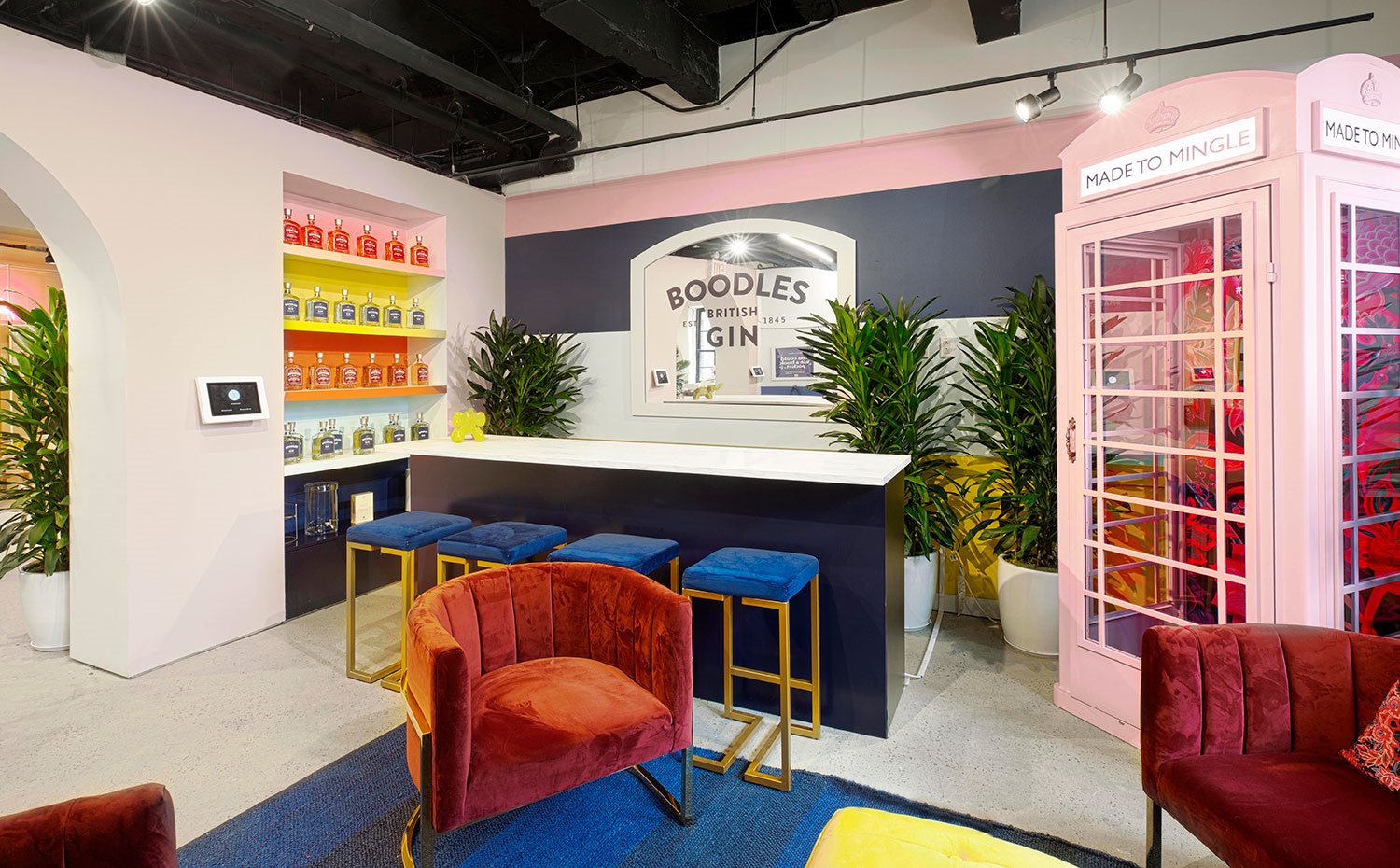 Inspiración bar con cabina telefónica en rosa, taburetes azules y butacas granate