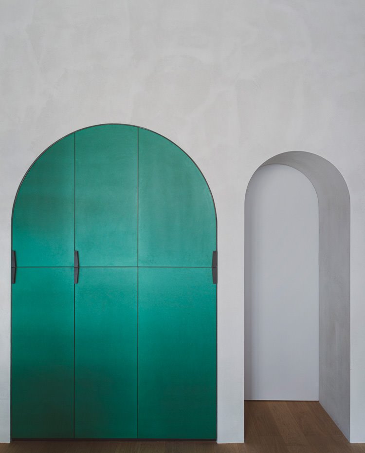 Armario encastrado en hueco en forma de arco, con frentes en verde y tiradores en negro