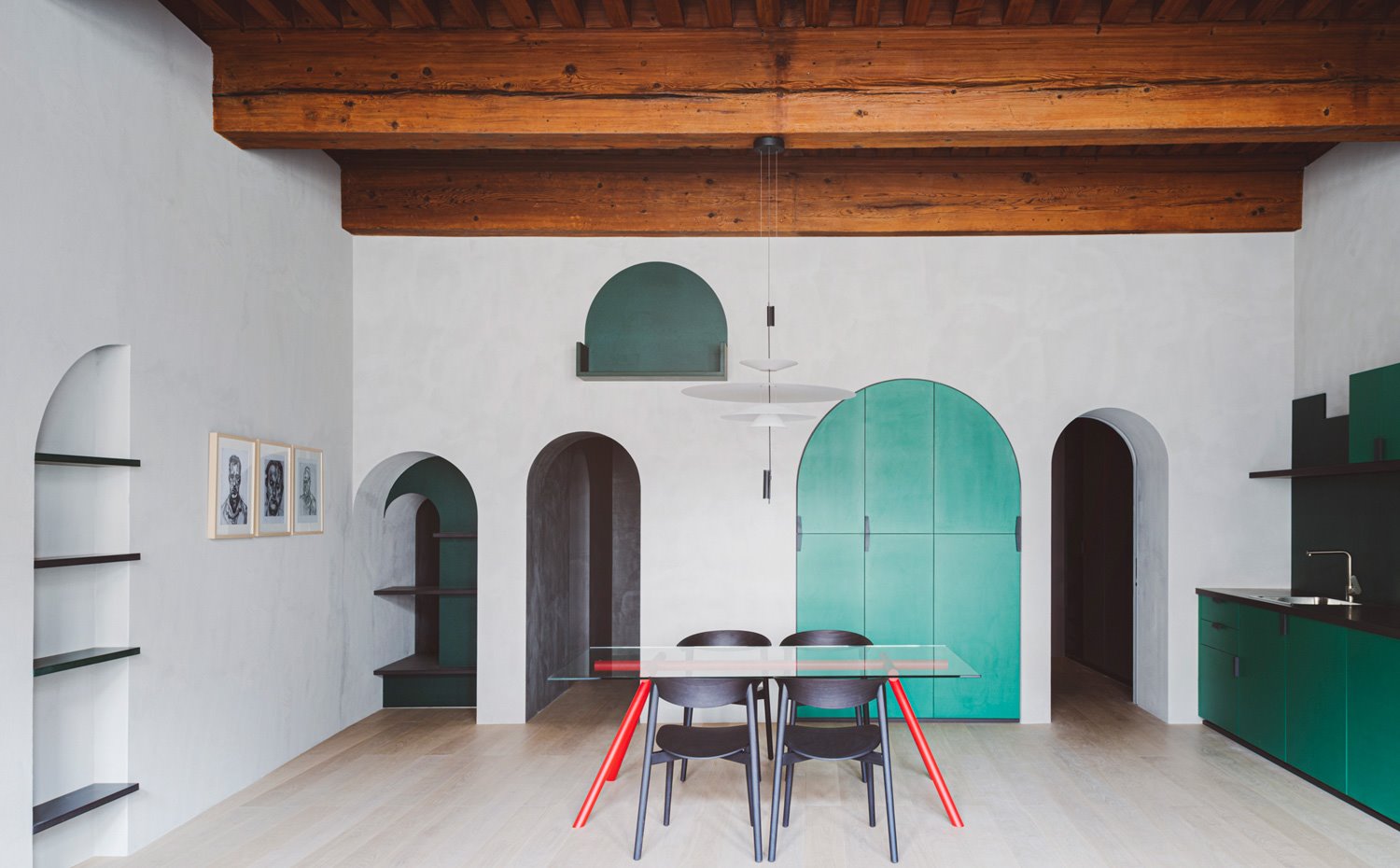 Comedor y cocina en espacio diáfano, mesa de comedor con sobre de cirstal y patal rojas, sillas negras