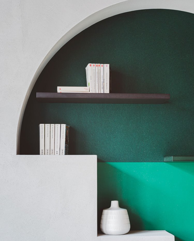 Detalle hornacina de salón a modo de estantería con baldas negras y frontal en verde