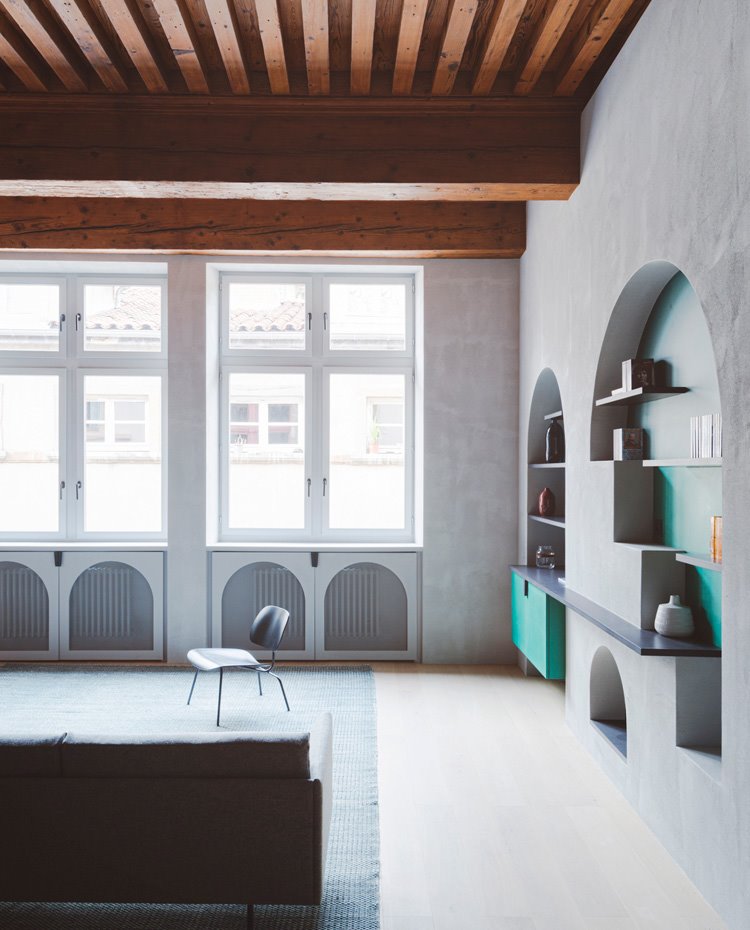 Techos de madera en zona de comedor, detalle decorativo de forma arquieada para ocultar los radiadores, estantes y módulos en verde en estructura en forma de arco