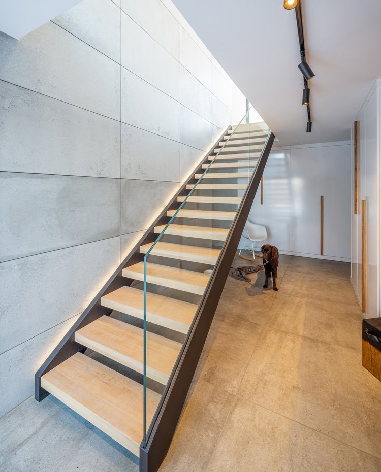 Escalera con peldaños de madera, pasamanos de cristal transparente, revestimiento en gris