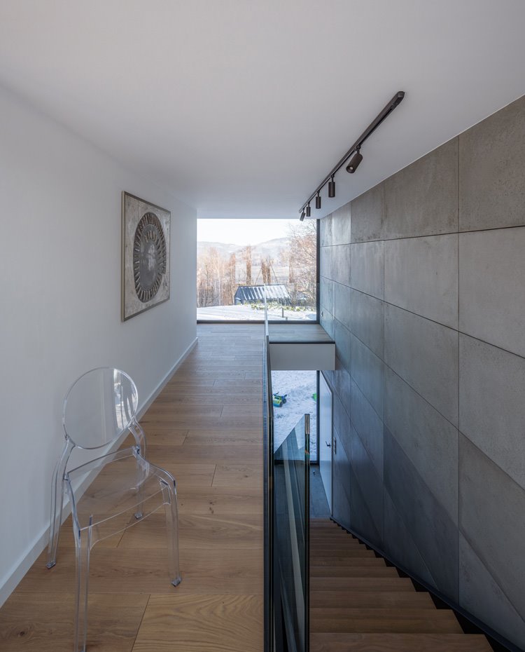 Zona de paso con silla transparente y suelo de madera