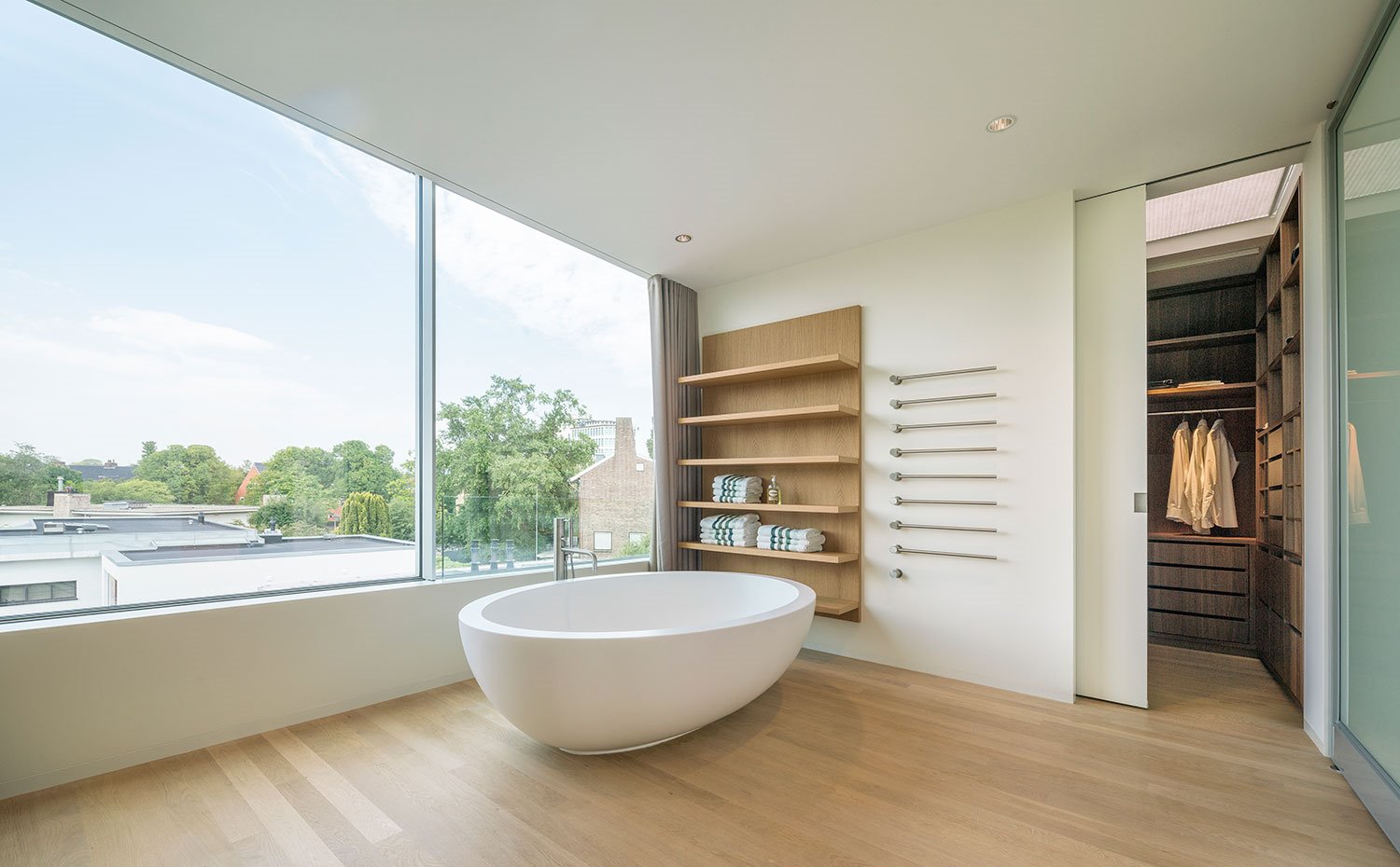 Cuarto de baño con bañera exenta de formas ovaladas y estantería de madera