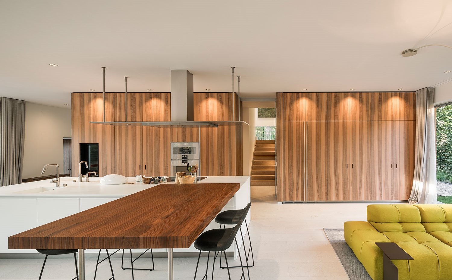 Mesa de madera y taburetes negros, junto a sofá color pistacho