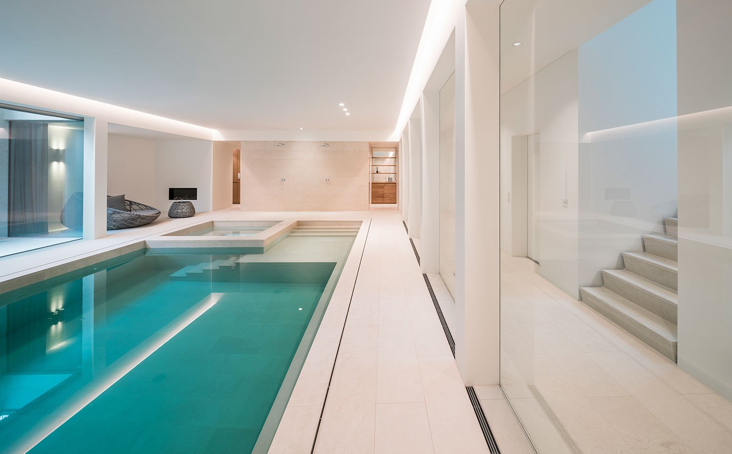 Piscina interior con revestimiento en tonos crema, zona acristalada