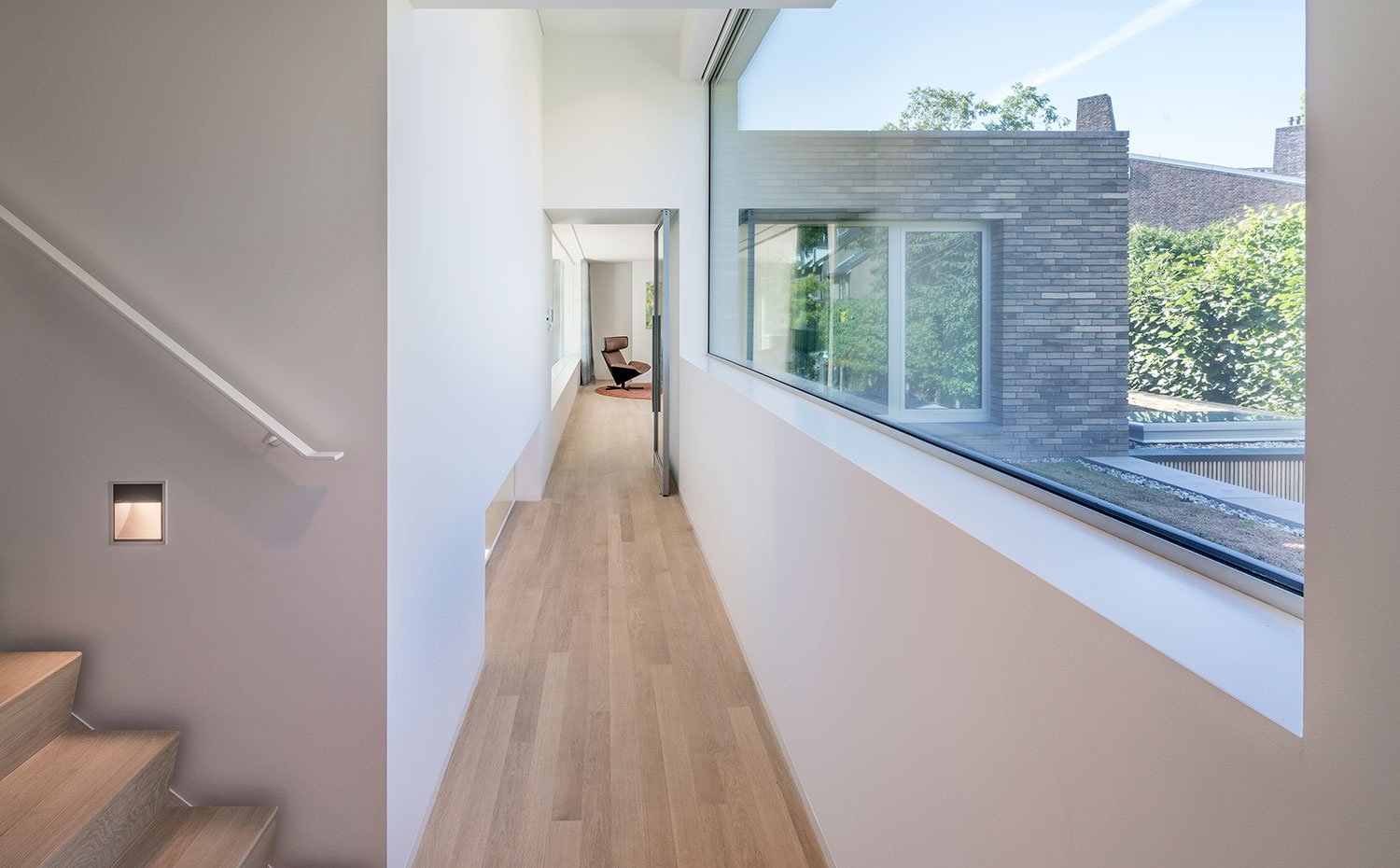 Zona de paso con revestimiento de madera y aperturas de cristal transparente