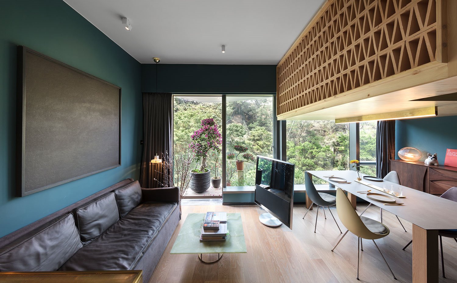 Sofá negro y mesa de centro de cristal, con televisor a modo de salón, junto a zona de comedor