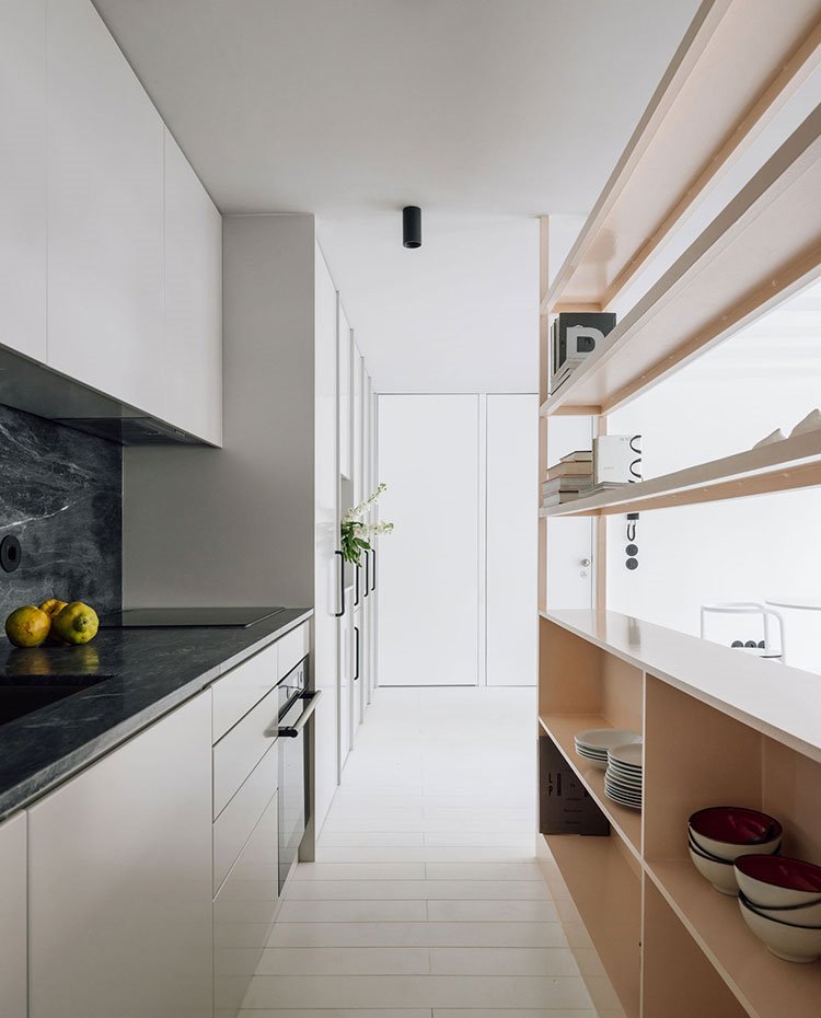 cocina abierta en línea con mueble separador a modo de estante y módulo abierto, encimera en negro