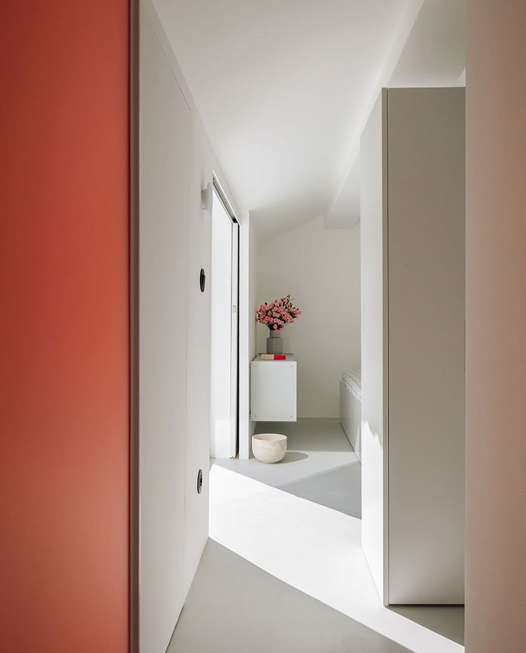Zona de paso hacia dormitorio con puerta en color teja y módulo suspendido en la parte final