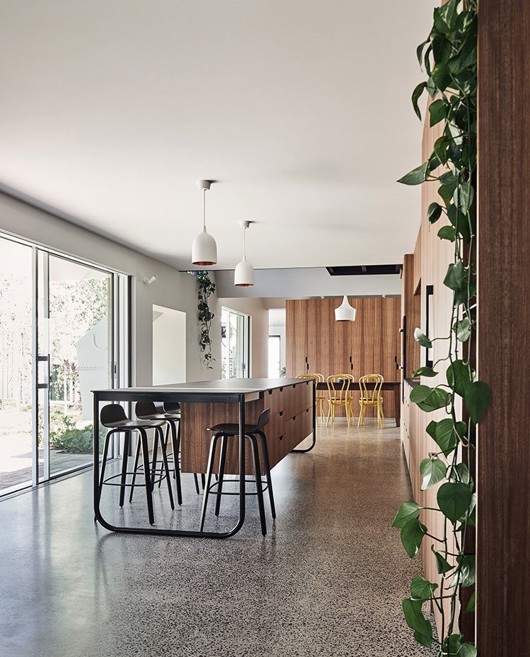 Isla de trabajo en cocina con zona de office, luminarias suspendidas en blanco