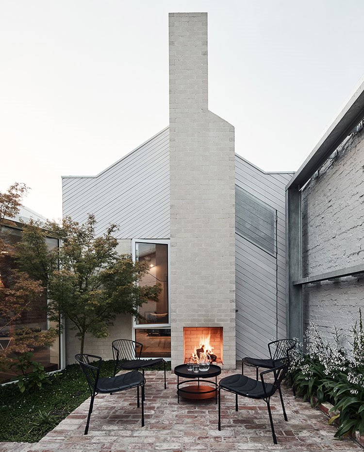 Zona de estar exterior con chimenea y mobiliario negro exterior