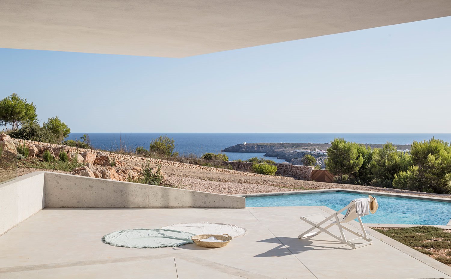 Plataforma de hormigón frente a piscina y con vistas del mar de fondo