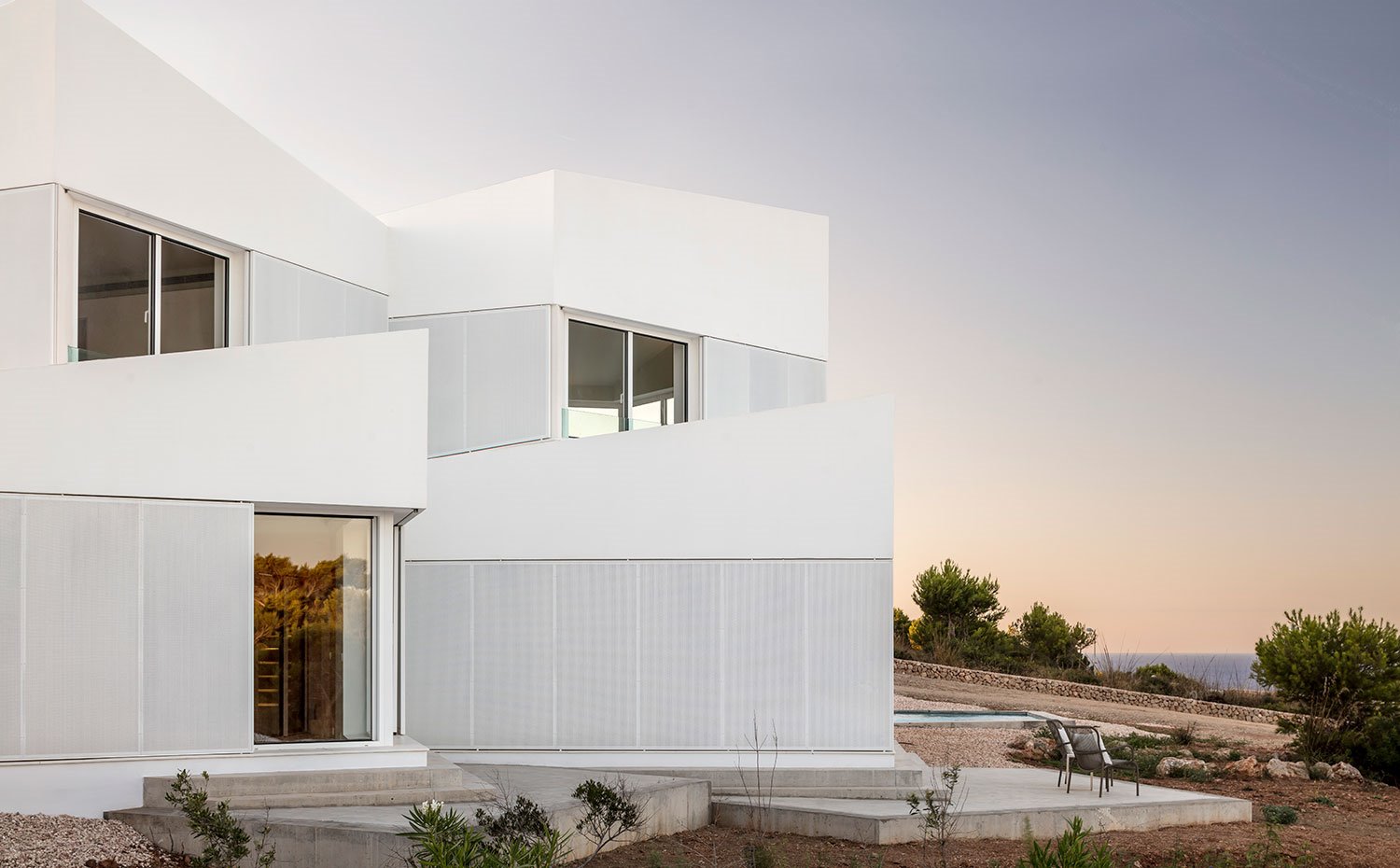Vista trasera de la fachada de la vivienda con grandes aperturas de cristal