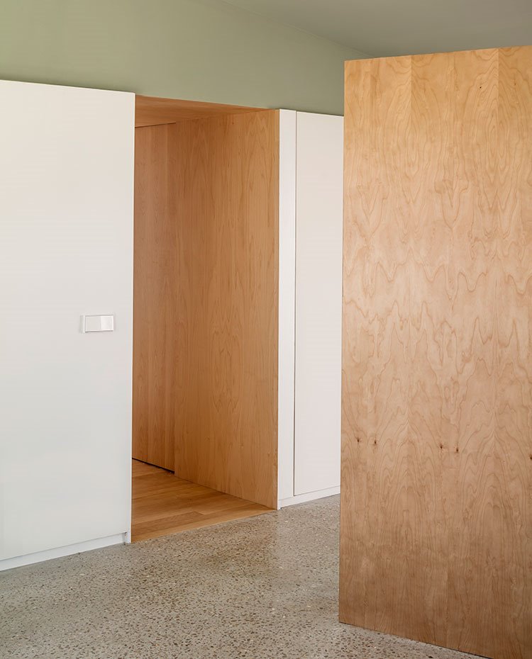 Zonas de paso recubiertas de madera, paredes blancas, techos en verde y suelo de granito