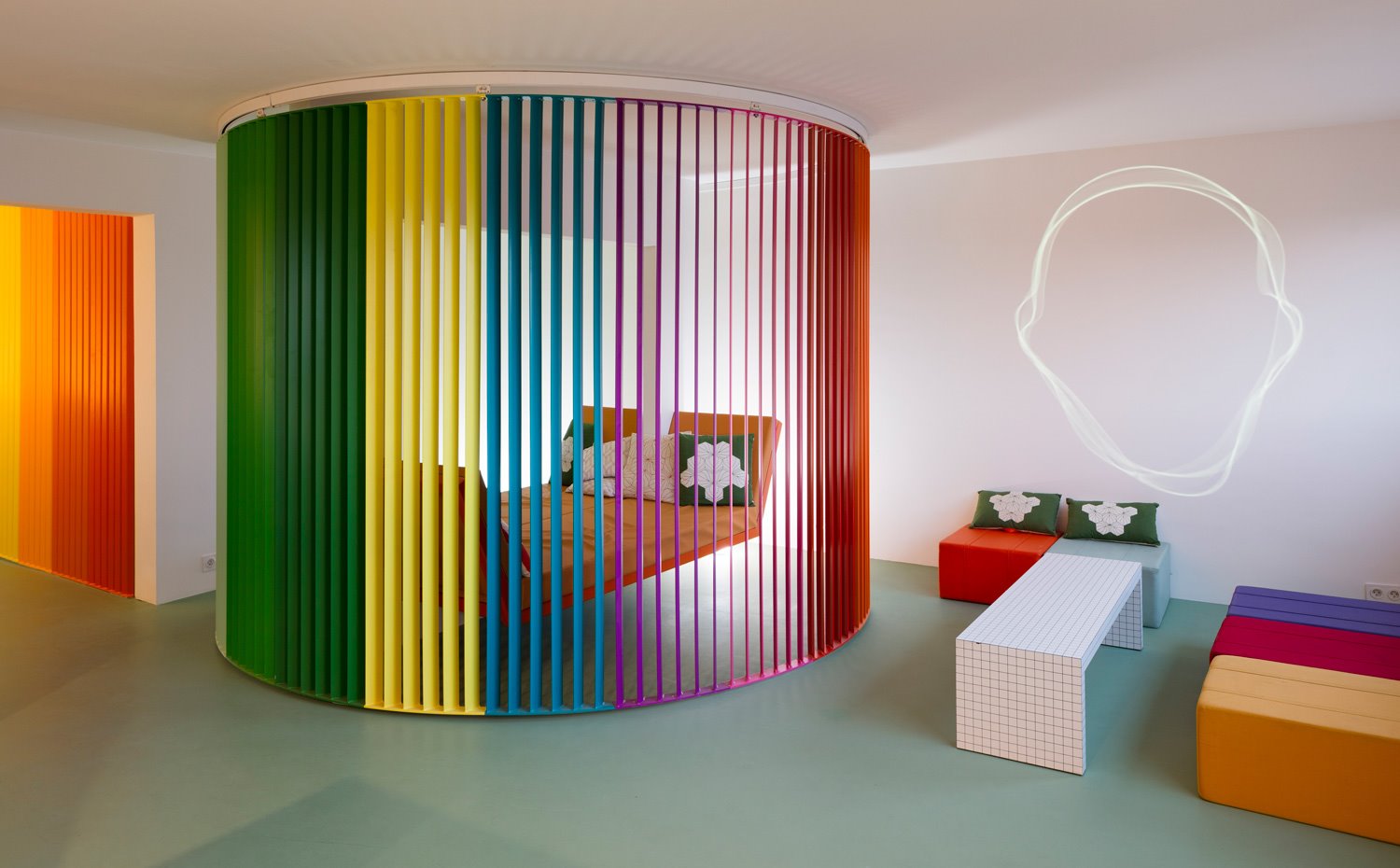 biombo cerrado dejando entrever la estructura suspendida de sofá-cama naranja, mesa de centro rectangular y pouf en forma de cubo