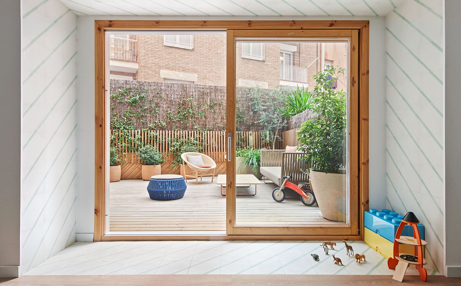 Acceso a terraza con cerramiento acristalado y perfilería de madera, terraza exterior con suelo en tarima de madera