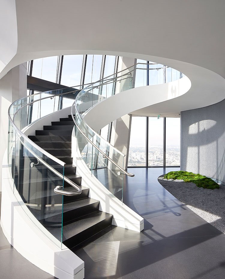 Escaleras curvas en blanco con peldaños y suelo en gris oscuro