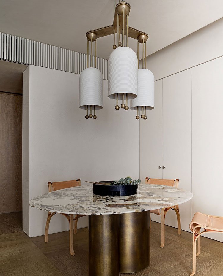 Zona de comedor, sillas de piel, mesa circular con sobre de piedra, base cromada, suelo de madera