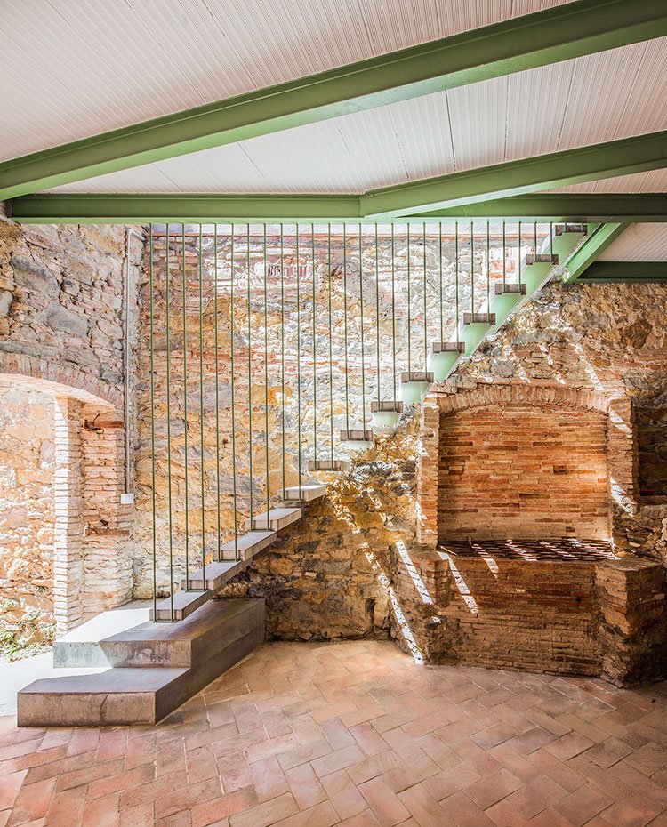 Escaleras con peldaños de cemento y estructura de hierro, techo con vigas de hierro en verde, pared de piedra