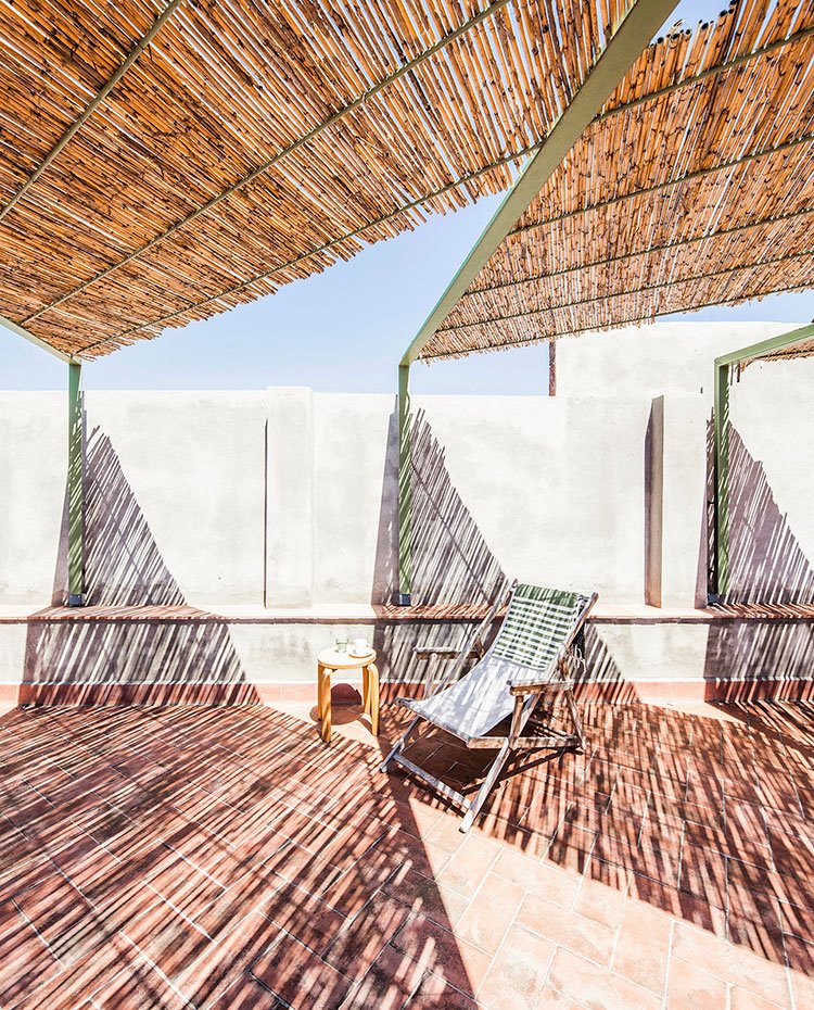 Estructura exterior de terraza recubierta en hormigón con hamaca y mesita auxiliar de madera