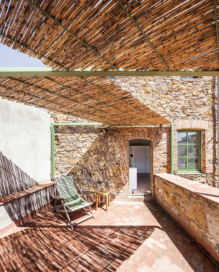 Terraza con suelo de terrazo, estructura de padera y vigas de hierro y protector de cubierta en fibras naturales