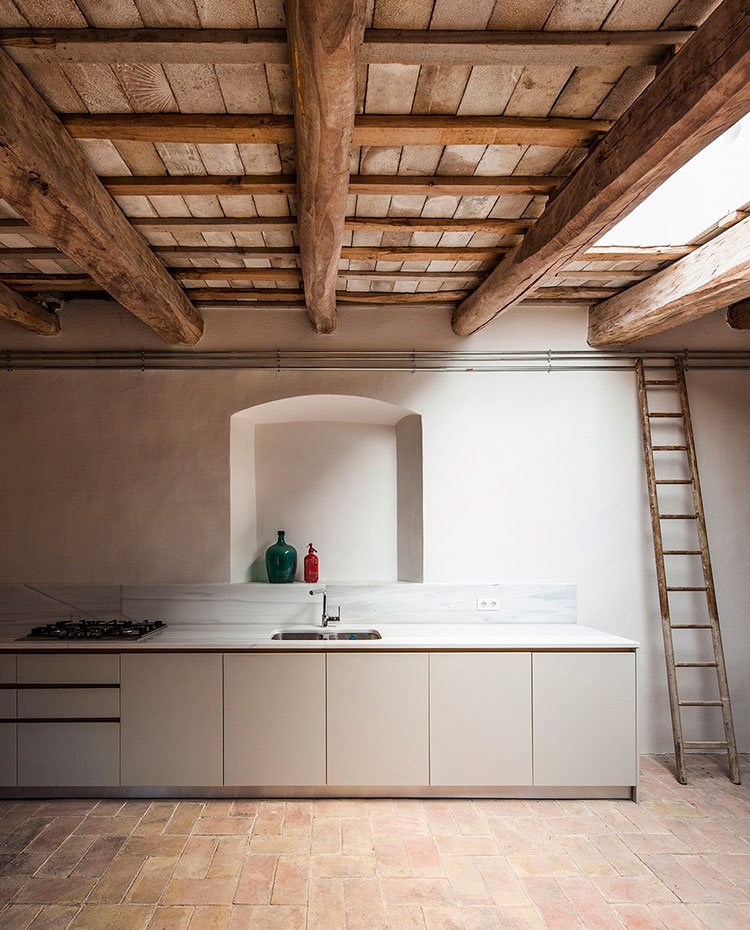 Viga y techos de madera, escalera de madera hacia huecos superior, hornacina sobre salpicadera de cocina, mobiliario bajo con frentes en blanco