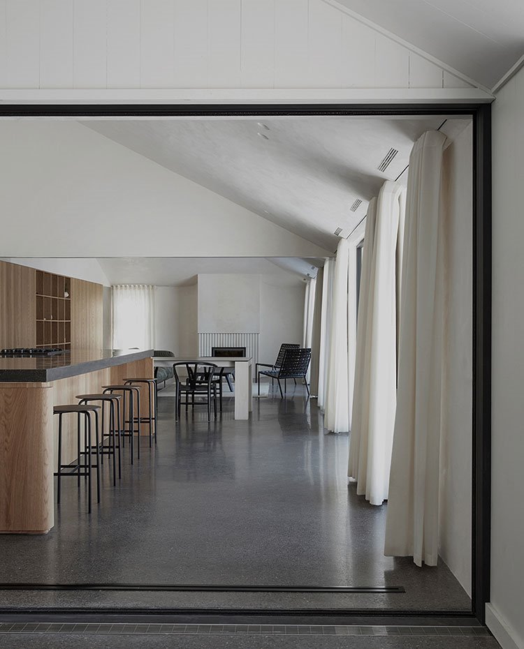 Cerramiento de cristal con perfil de aluminio hacia cocina y salón con chimenea en el fondo