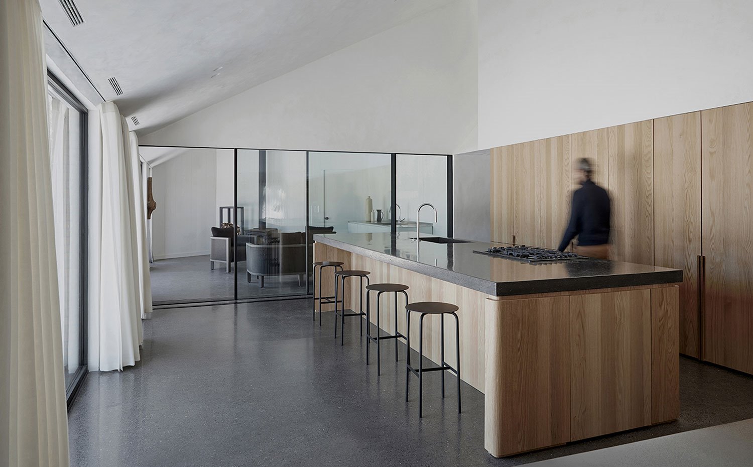 Cocina con altos techos inclinados y cerramientos acristalados hacia otra estancia de estar y hacia el exterior