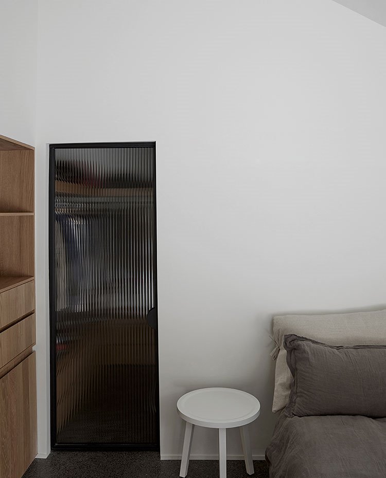 Dormitorio con puerta en cristal esmerilado, mesilla en blanco y armarios en madera