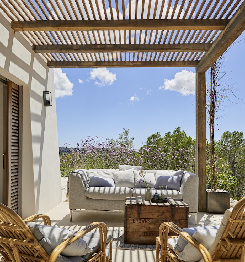 Terraza con pergola de madera y sillones de color gris