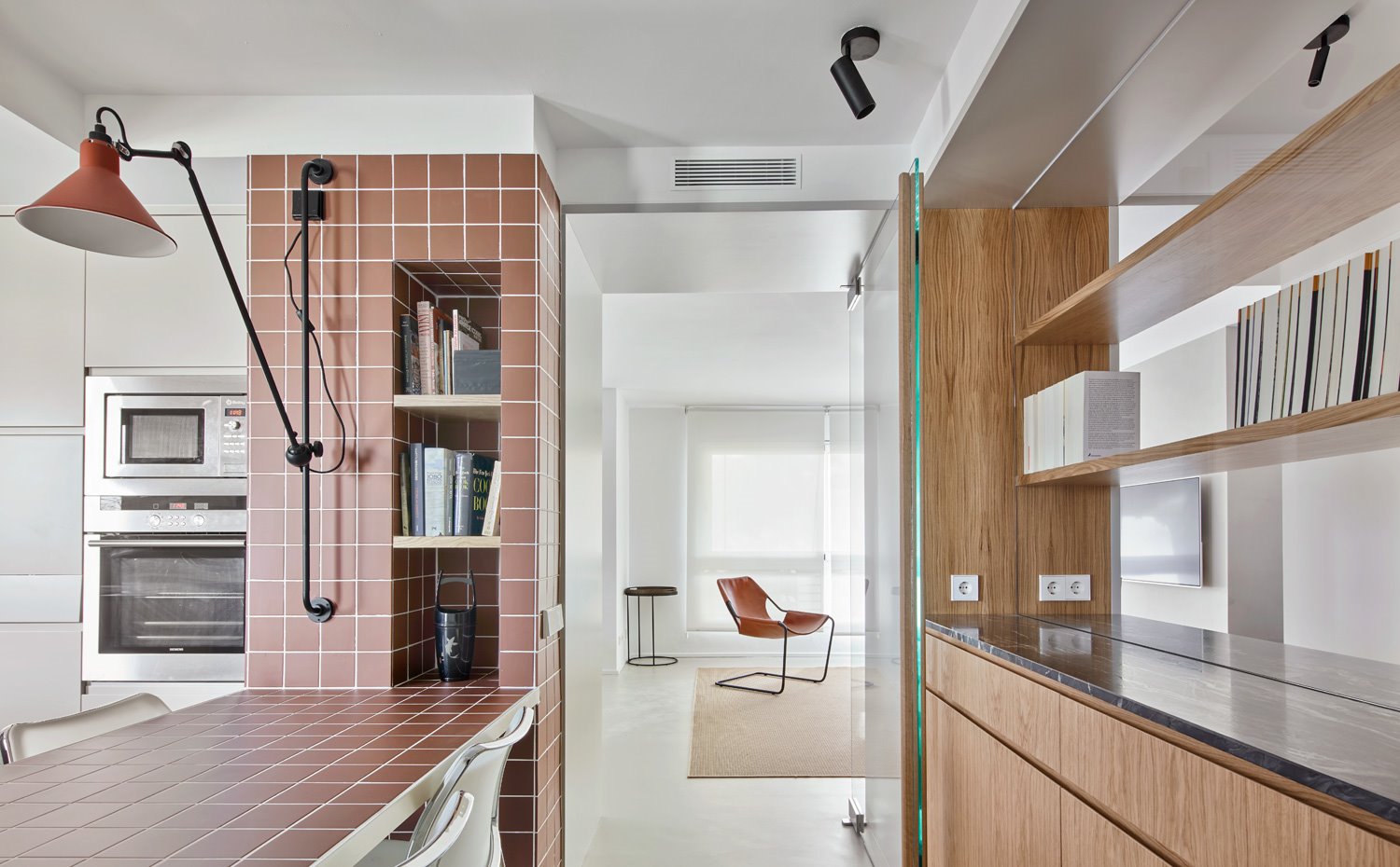 Cocina con mesa de office, estantería a modo de hornacina y gran aplique extensible en pared 