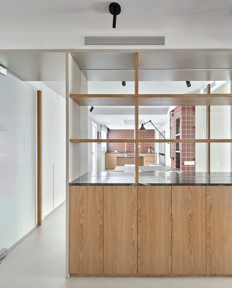 Módulo de carpintería de obra como mueble divisor con la cocina al fondo, puerta de cristal transparente